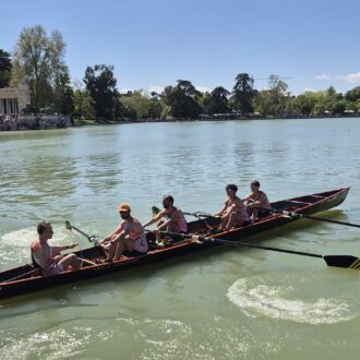 Cuatro deportistas remando en yola y timonel
