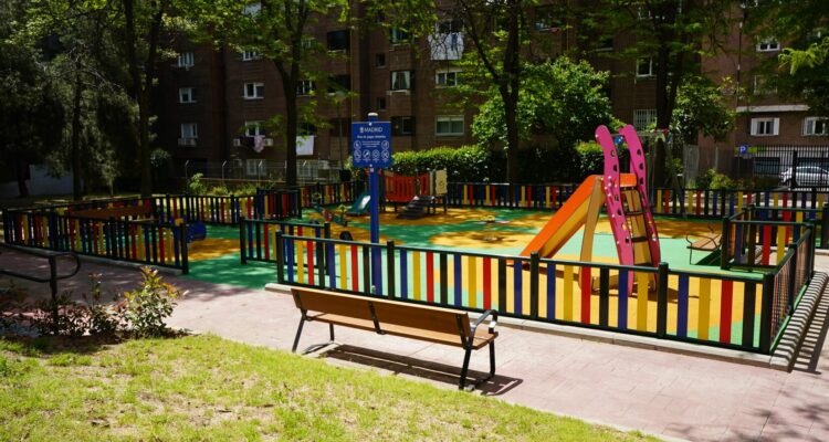 imagen de un parque infantil con un tobogán y una zona vallada de colores