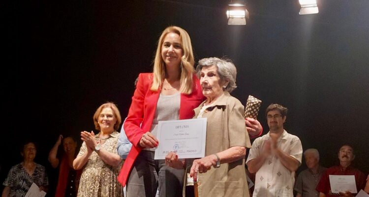 una persona joven junto con una persona mayor sujetando un diploma
