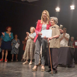 una persona joven junto con una persona mayor sujetando un diploma