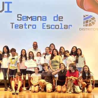 El concejal de Carabanchel con los niños de colegios que han participado en el certamen de teatro sobre una tarima de un escenario