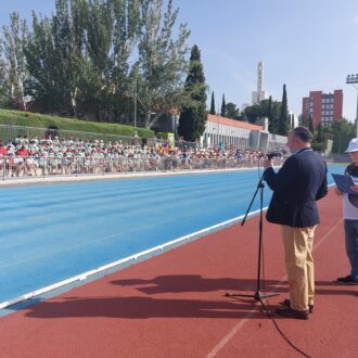El concejal de distrito, Nacho Pezuela, hablando en una pista de atletismo con los participantes de la 8 jornada de inclusión de Moratalaz en la grada