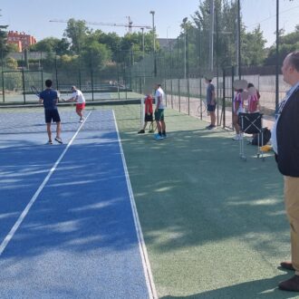 El concejal de Moratalaz, Nacho Pezuela, en una pista de tenis con adolescentes participantes en el campamento