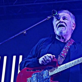 Un guitarrista en un escenario con un guitarra roja