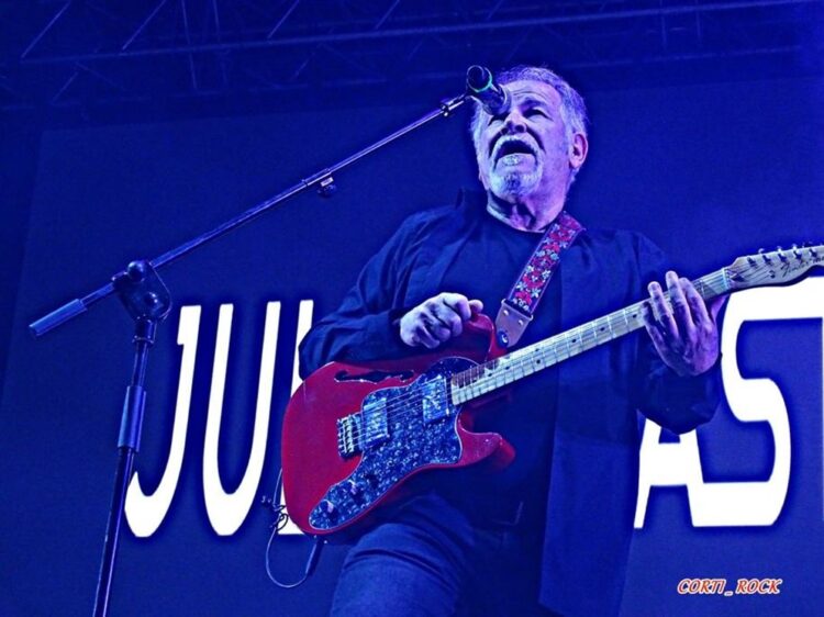 Un guitarrista en un escenario con un guitarra roja