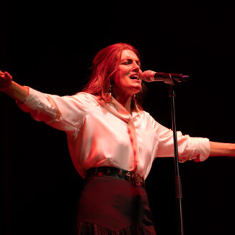 Mónica Molina con los ojos cerrados y los brazos abiertos cantando en su actuación de 'Algo Inesperado' de Veranos de la Villa