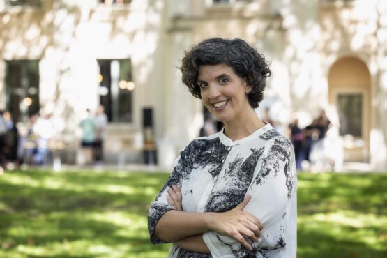 Una mujer posando delante de un edificio en un jardín