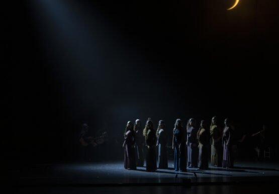 unas personas sobre un escenario oscuro con la media luna de fondo