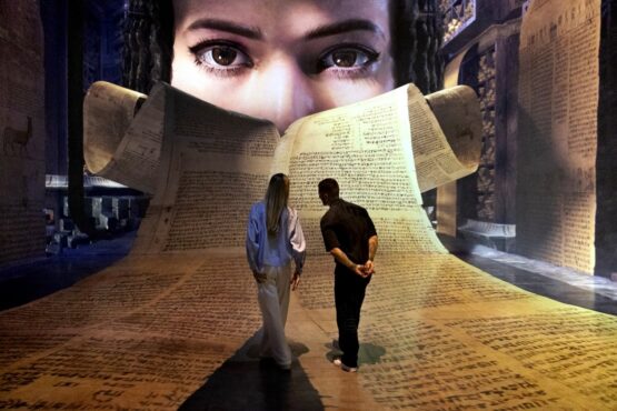 Imagen de la exposición Cleopatra con unas personas caminando sobre un pergamino