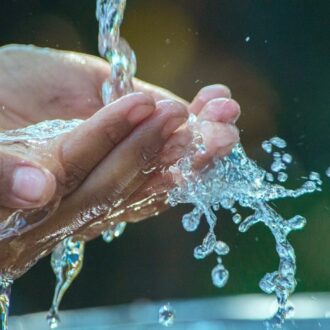 Agua de una fuente pública de Madrid cayendo en las manos de un viandante