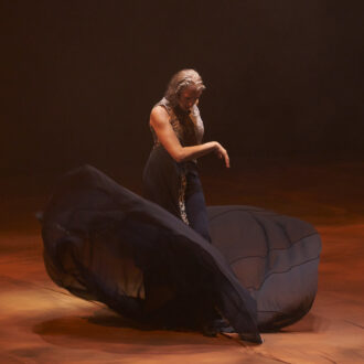 una bailaora sobre un escenario con un vestido negro en movimiento