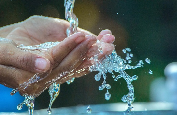 Agua de una fuente pública de Madrid cayendo en las manos de un viandante
