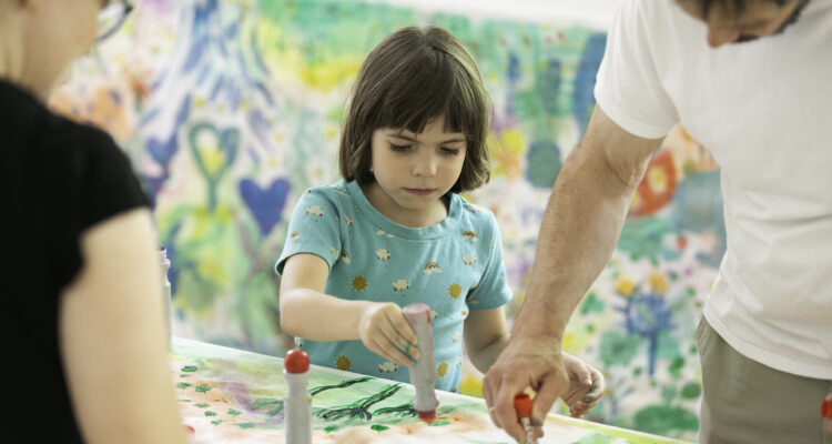 Una niña acompañada de sus padres haciendo manualidades