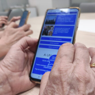 unas manos de una persona mayor manejando un móvil que refleja la web accesible del ayuntamiento de madrid
