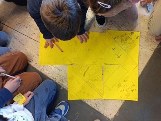 Niños alrededor de unas hojas amarillas en el taller 'corro y recorro mi barrio', uno de los planes de la agenda cultural del fin de semana