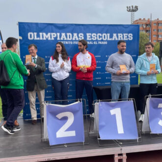 El concejal de Fuencarral-El Pardo, José Antonio Martínez Páramo, en la entrega de trofeos de las Olimpiadas Escolares del distrito entregando un premio a uno de los ganadores en la tarima escenario del podio, junto a más galardonados y público infantil participante viéndoles desde abajo