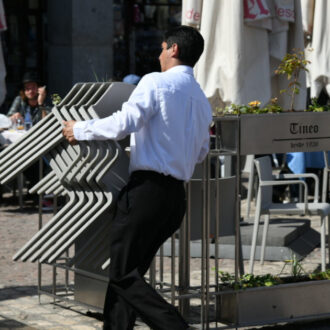 Imagen de archivo de un trabajador de hostelería colocando las sillas de una terraza de la Plaza Mayor de Madrid
