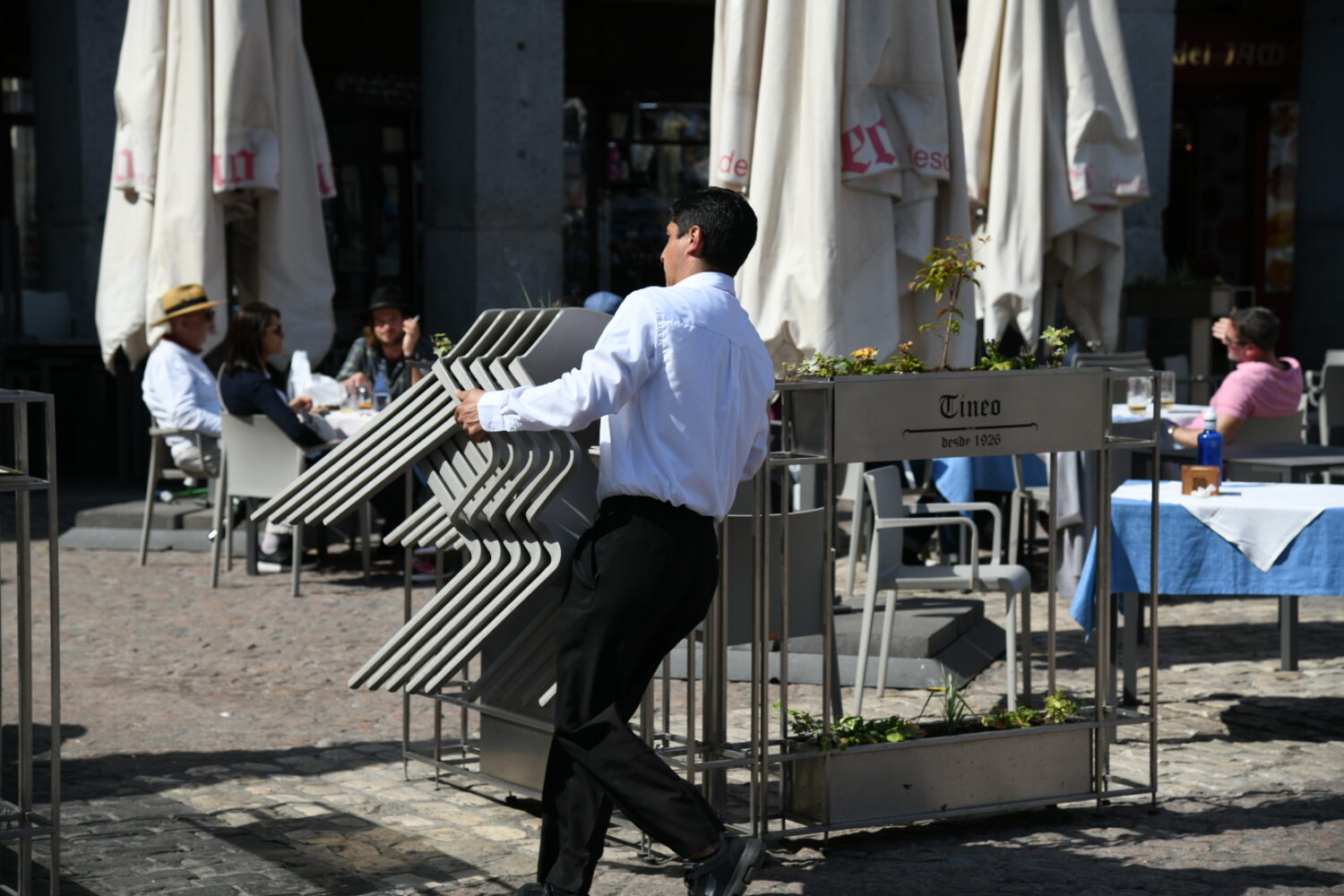 Imagen de archivo de un trabajador de hostelería colocando las sillas de una terraza de la Plaza Mayor de Madrid