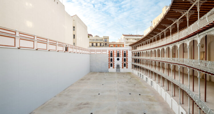 Vista amplia de la cancha del frontón Beti Jai, rodeada por graderíos curvos de hierro restaurados y edificios del entorno, donde Rosalía hizo la entrevista sobre Lux