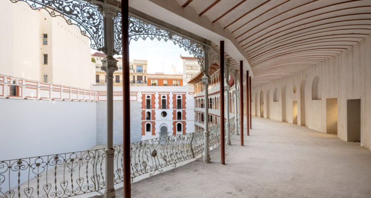 Pasillo cubierto del frontón Beti Jai con estructura de hierro forjado y vistas a la cancha central.
