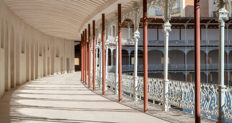 Galería superior del frontón Beti Jai, con columnas metálicas y barandillas ornamentadas que rodean el graderío curvo.