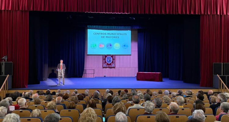 El concejal del distrito, Alberto González, en el escenario del Auditorio Paco de Lucía, en la presentación de la Semana de Mayores, con público asistente