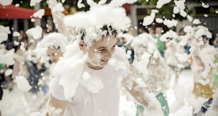 Varios niños juegan con la espuma en una actividad de prevención de incendios organizada por Bomberos de Madrid
