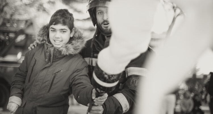 Un miembro del Grupo Pedagógico de Bomberos de Madrid enseña a un niño el funcionamiento de una manguera