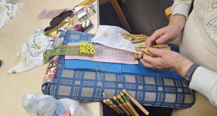 Manos de uno de los socios del centro haciendo encaje de bolillos