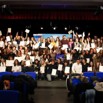 Loa nuevos funcionarios posan con sus títulos en el escenario durante el acto