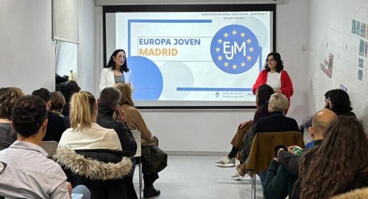 Dos ponentes presentan el programa Europa Joven Madrid ante un público sentado en una sala, con una pantalla al fondo que muestra el logotipo EJM y el título de la iniciativa