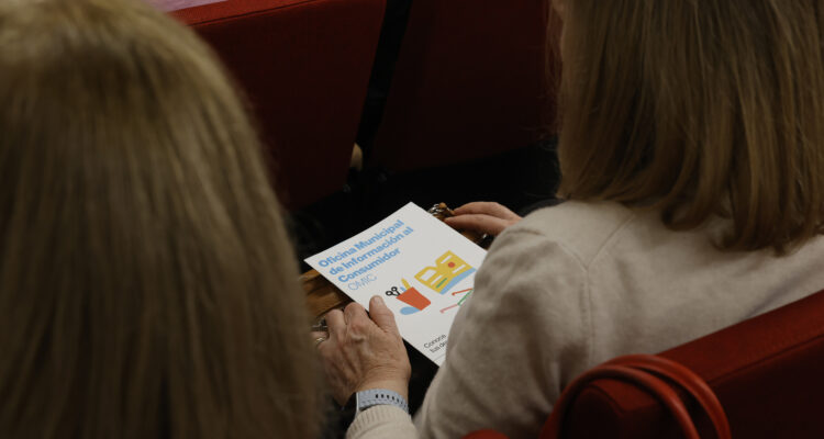 Asistente con folleto informativo de la Escuela Municipal de Consumo