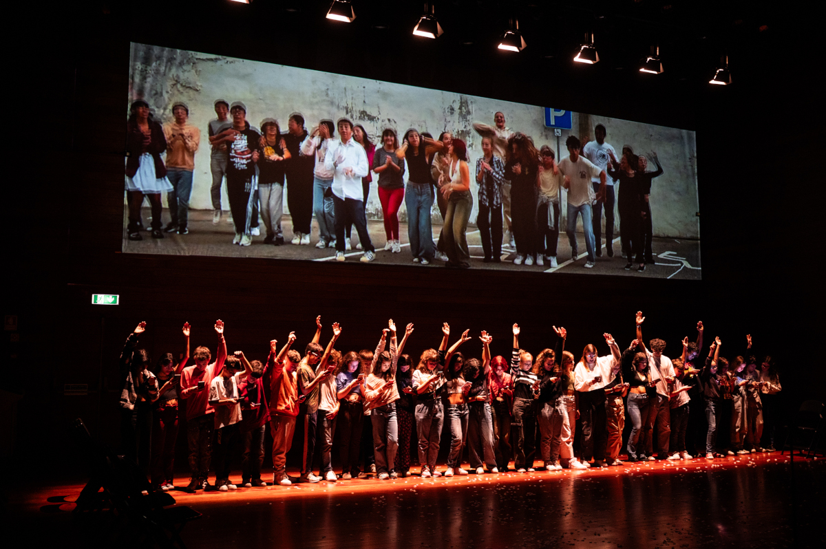 Grupo de jóvenes en escenario durante una representación teatral participativa