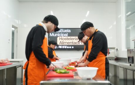 Alumnos de la Escuela Municipal de Hostelería y Alimentación de Madrid preparando verduras en una cocina profesional durante un curso gratuito.