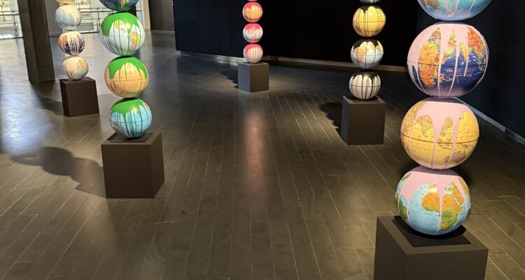 Instalación artística con globos terráqueos intervenidos en una sala de exposición