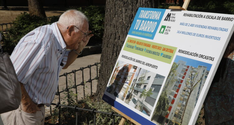 Ciudadano mirando cartela Plan Transforma tu Barrio (imagen de archivo)