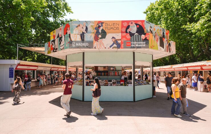 Caseta institucional compartida por el Ayuntamiento de Madrid y la Comunidad de Madrid en la 85ª Feria del Libro, decorada con ilustraciones de la temática Buen Humor, rodeada de visitantes
