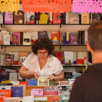Visitantes consultan libros en una caseta de la Feria del Libro de Madrid 2026 en el parque de El Retiro.