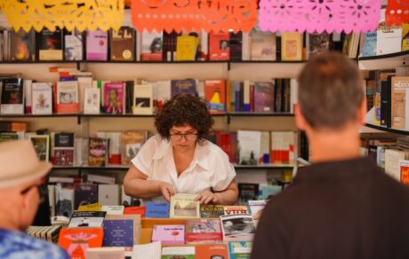 Visitantes consultan libros en una caseta de la Feria del Libro de Madrid 2026 en el parque de El Retiro.