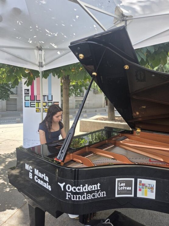 Joven pianista interpreta una pieza en un piano de cola instalado al aire libre durante una actividad del festival Cultuletras 2026 en el Barrio de las Letras.