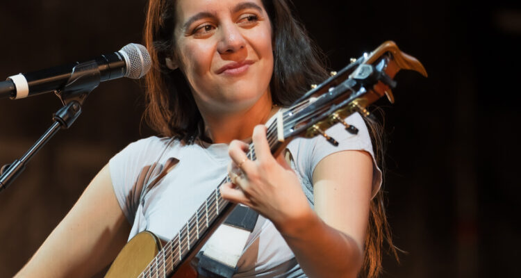 Valeria Castro sonriendo mientras toca la guitarra en el escenario de Conde Duque