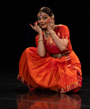 La artista india, Malvika, en el escenario con vestido rojo