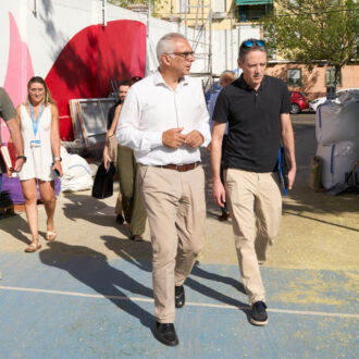 Visita a las obras de mejora en colegios de Carabanchel, con personal técnico recorriendo un patio escolar donde se están realizando trabajos de renovación y acondicionamiento de instalaciones educativas.