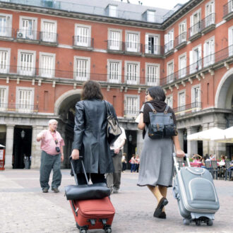 Viajeros con maletas cruzan la Plaza Mayor