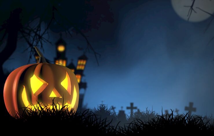 Calabaza de Halloween iluminada con una cara terrorífica, rodeada de cruces y lápidas en un cementerio nocturno.