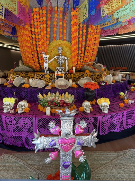 Altar de muertos del Teatro Fernán Gómez con esqueletos, flores de cempasúchil, papel picado de colores, calaveras y ofrendas tradicionales mexicanas.
