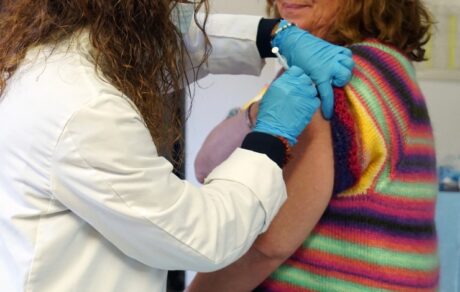 Profesional sanitaria administra una vacuna en el brazo de una mujer durante la campaña de gripe y COVID-19 en Madrid.